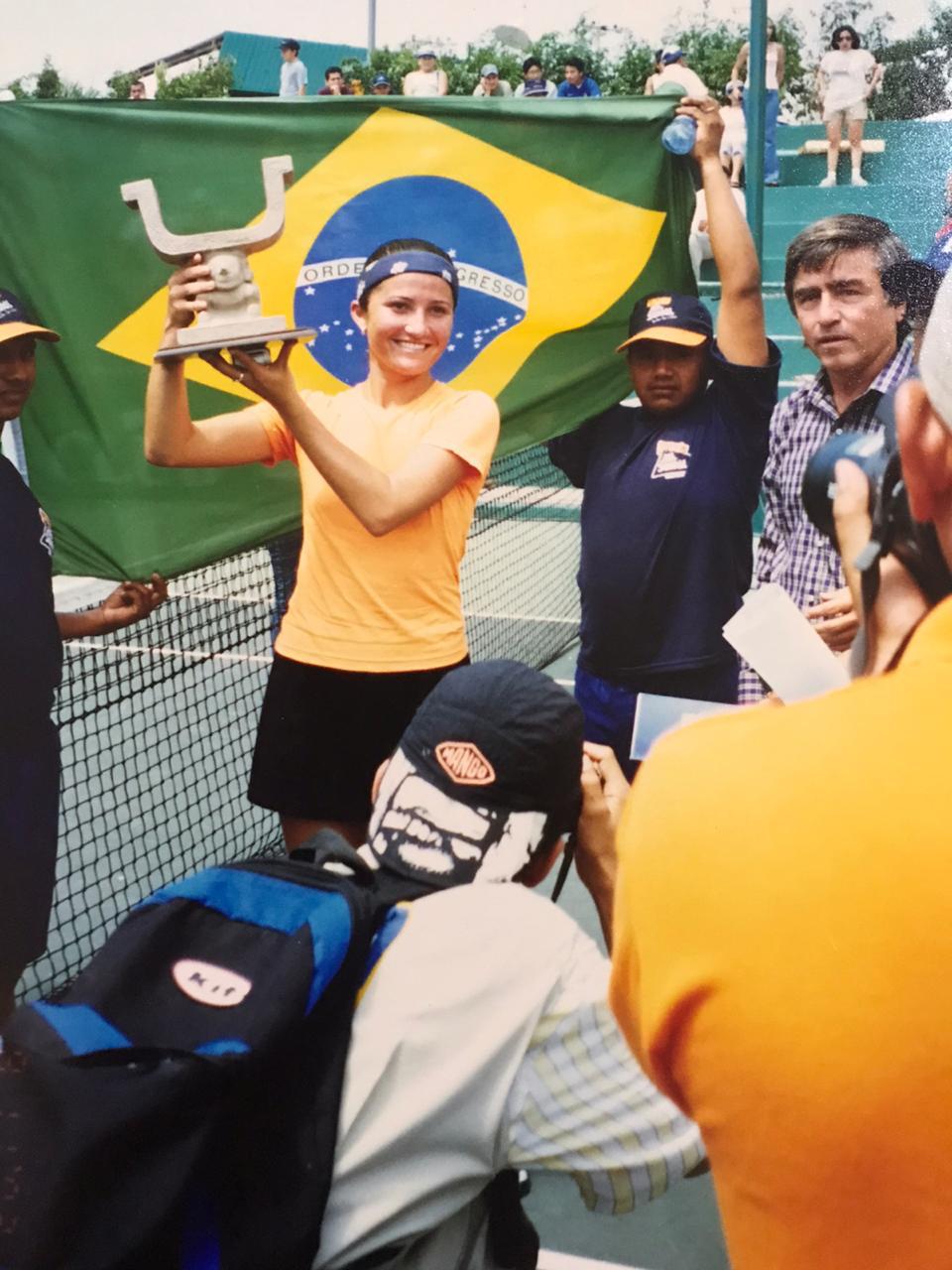 Bruna levanta o troféu. Ao fundo bandeira do Brasil