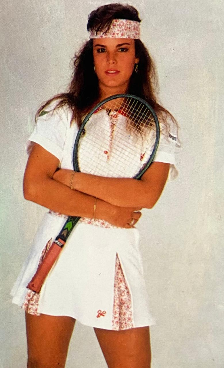 Atleta uniformizada posa para foto com raquete.