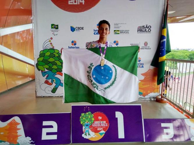 Atleta no pódio exibindo a bandeira do Paraná.