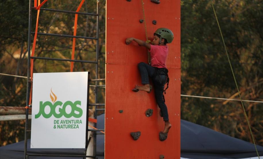 Menino subindo um paredão de escalada.