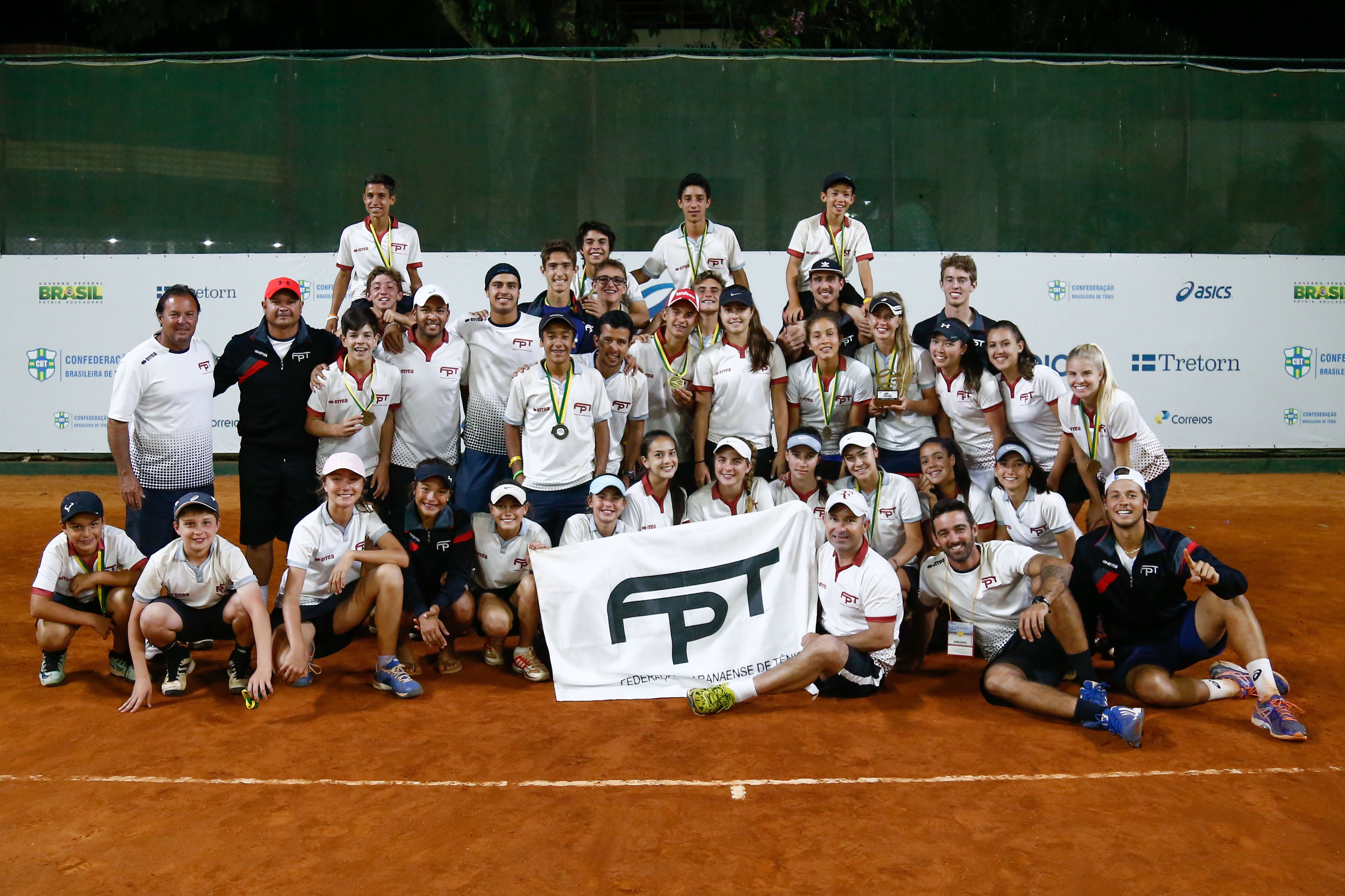 atletas fazem pose com medalhas, troféu e bandeira