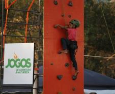 Menino subindo um paredão de escalada.