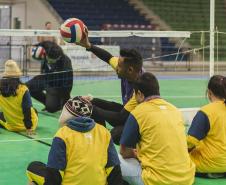 Professor voluntário ensina as crianças o vôlei sentado