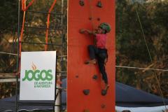 Menino subindo um paredão de escalada.