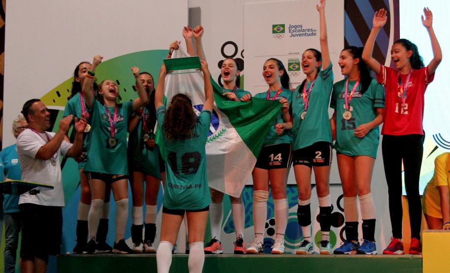 Meninas comemoram no pódio levantando o troféu