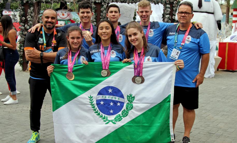 Atletas segurando bandeira do Paraná