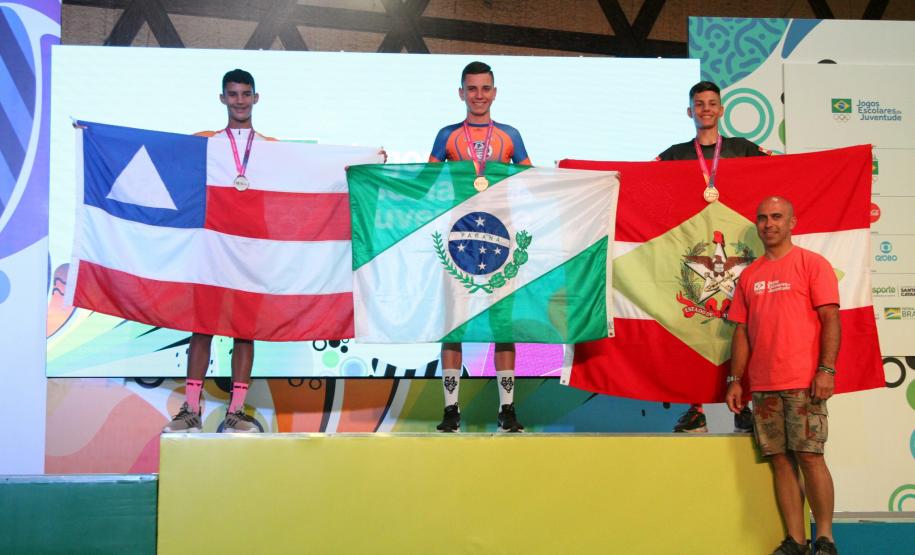 Ciclista no alto do pódio segurando a bandeira